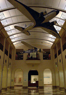 The Aviation Library and Museum is a hall with arches, balconies and a shiny marble floor. Model planes hang from the ceiling.